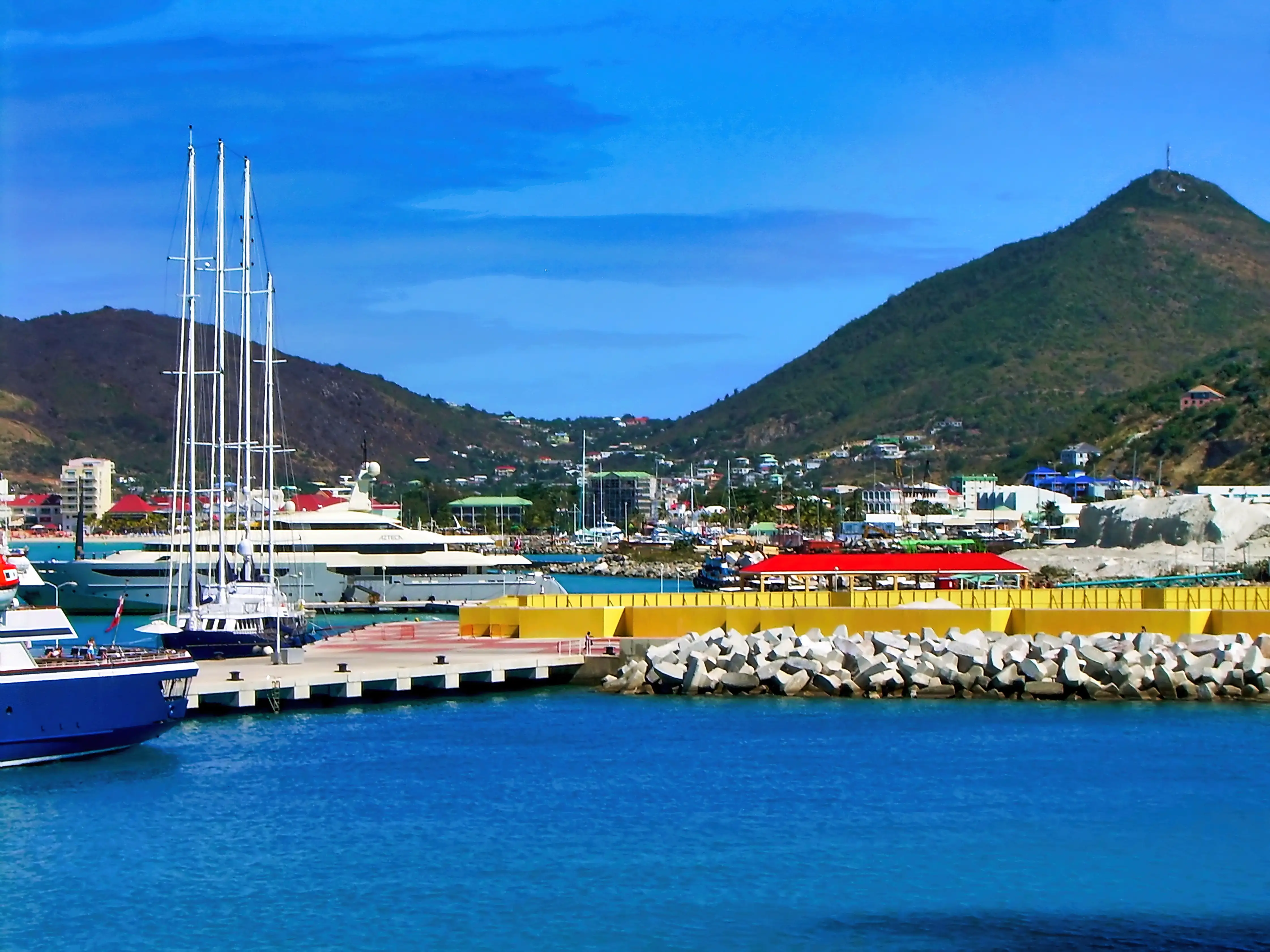 A wide view of two cruise ships tied up along the pier at Port St. Maarten, with the hills of the island behind them