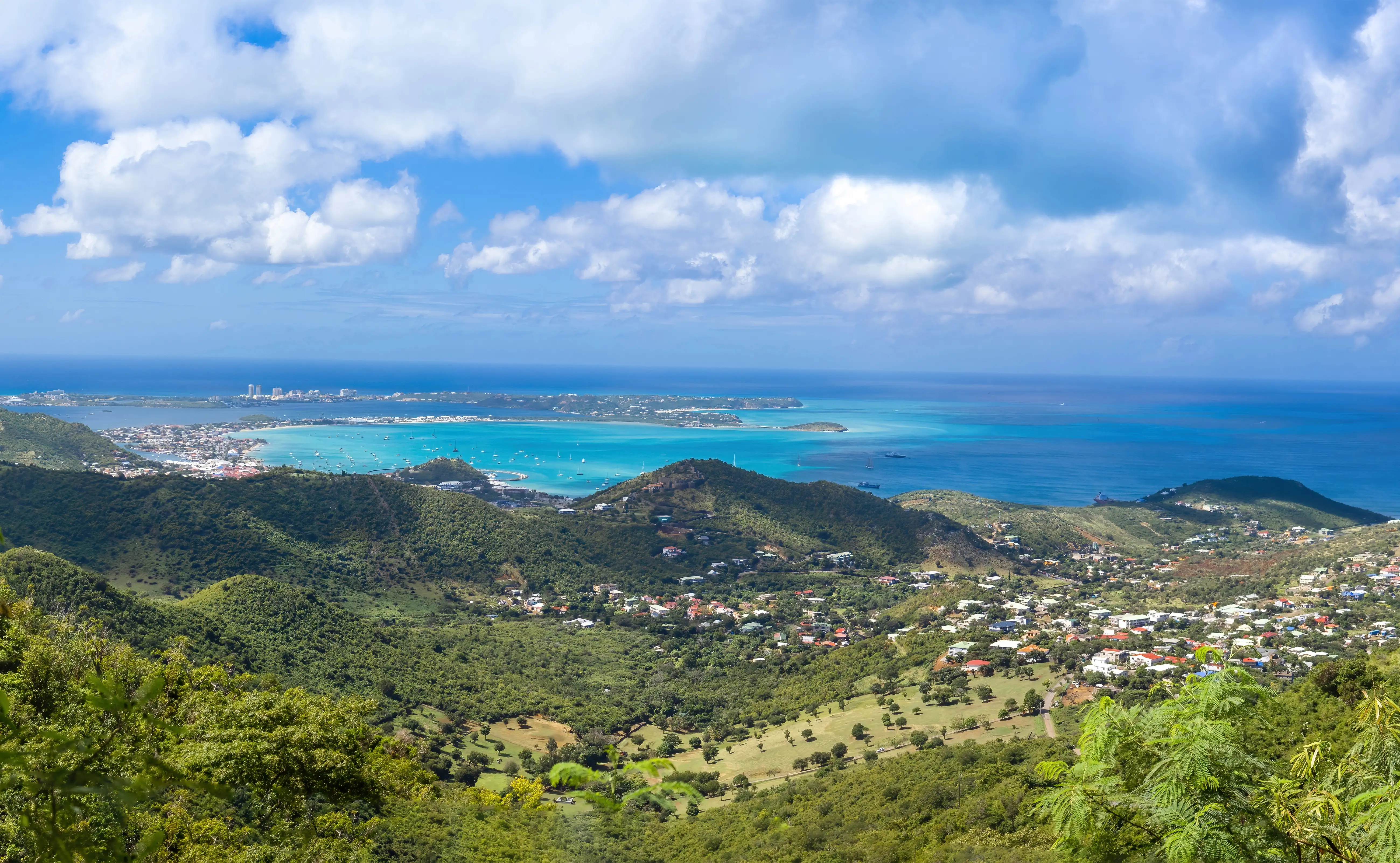 A sweeping view from the Pic Paradis lookout over Saint Martin's hills, town, and turquoise lagoon below.