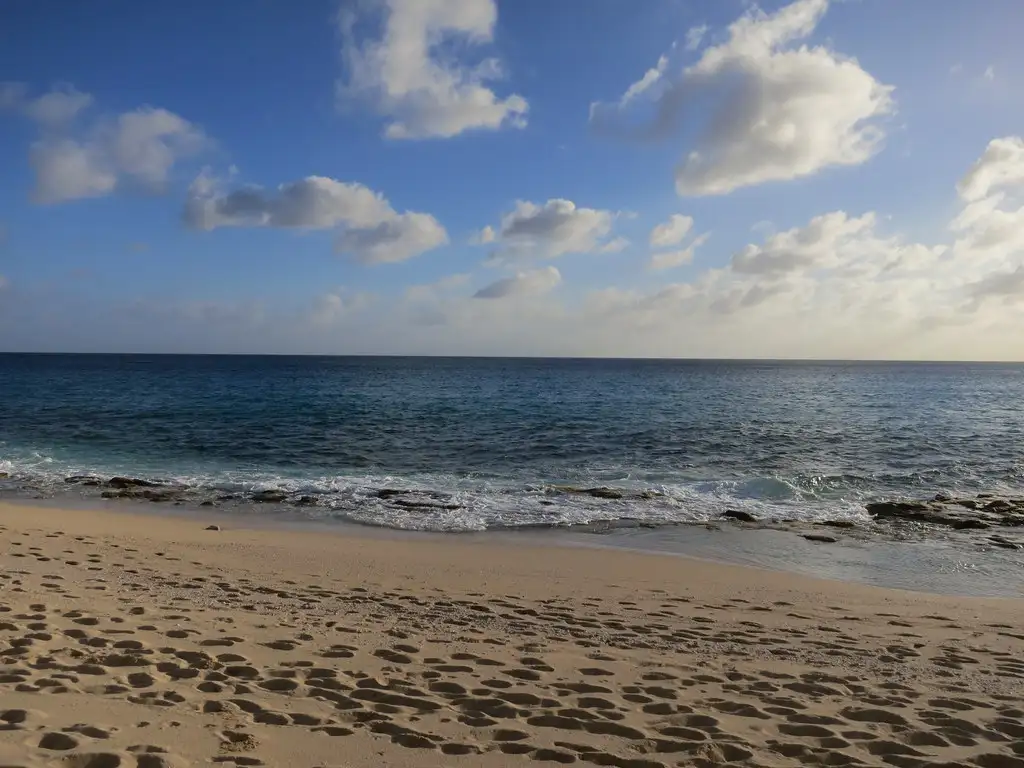 Looking along the empty sand of Baie Longue with the Caribbean on one side and the beach running away to a distant point