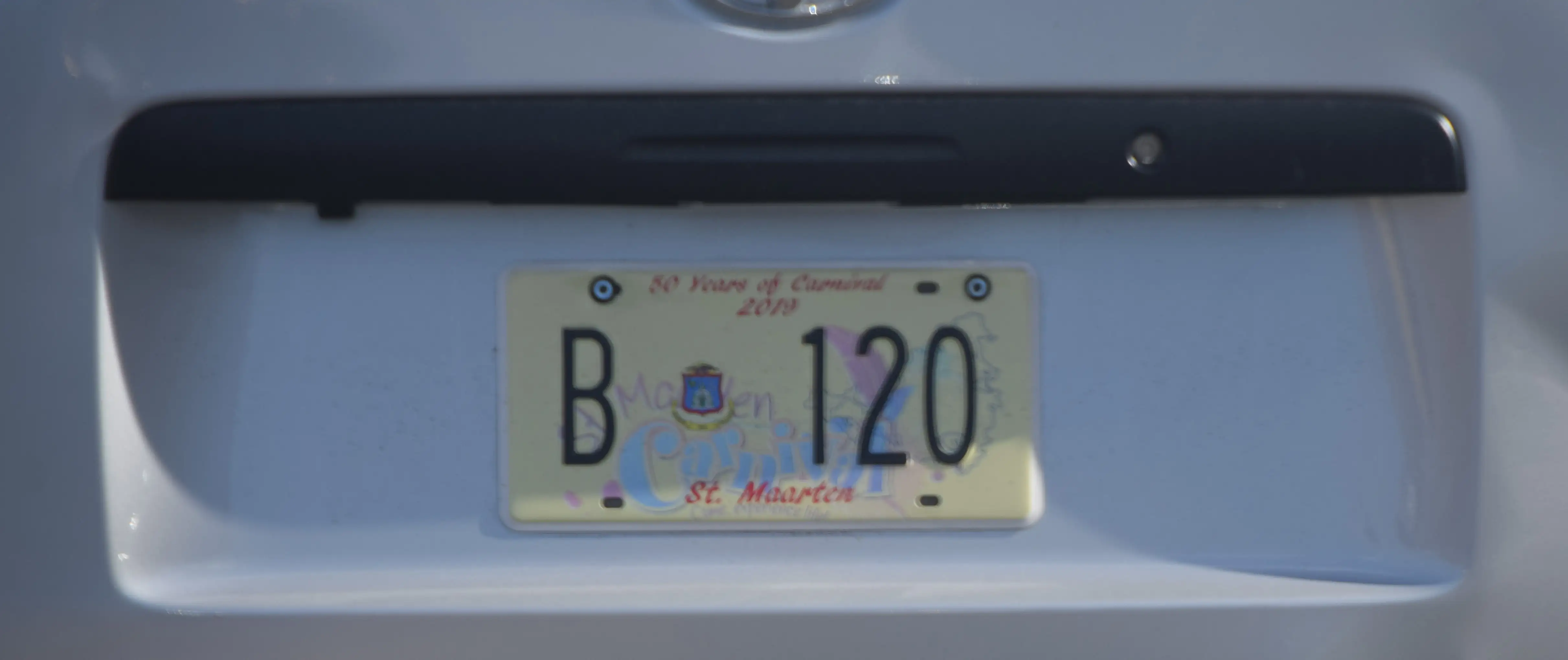 A Sint Maarten licence plate reading B 120 mounted on the back of a vehicle, with the island coat of arms between the letter and the numbers