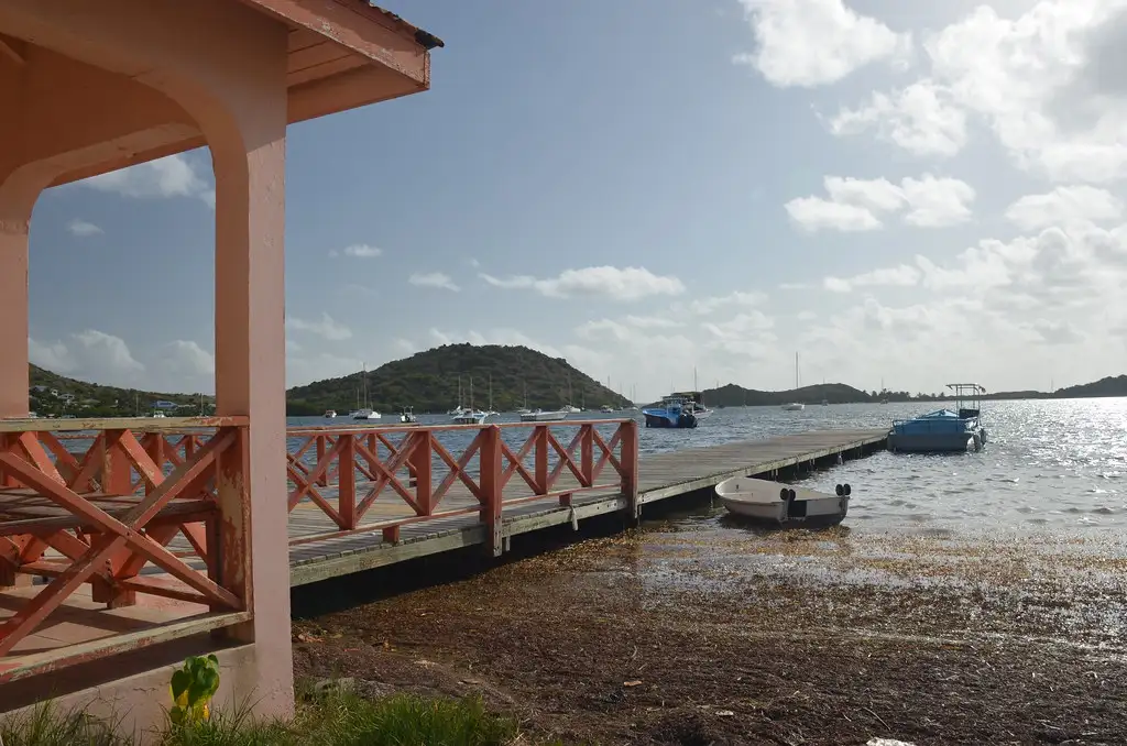 A small wooden ferry dock on a calm bay, the jetty where boats leave for Pinel Island