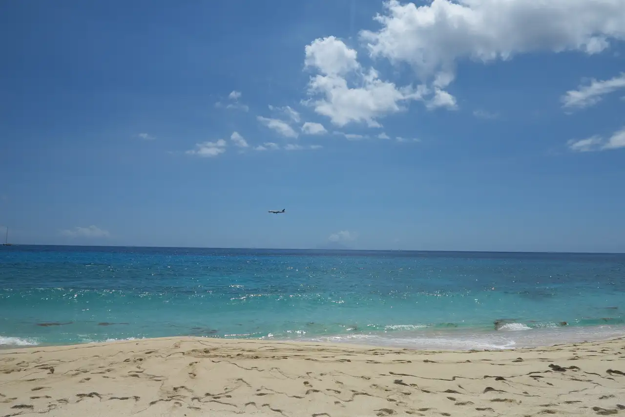 Empty sandy beach at Cupecoy with footprints in the sand and the island of Saba on the horizon