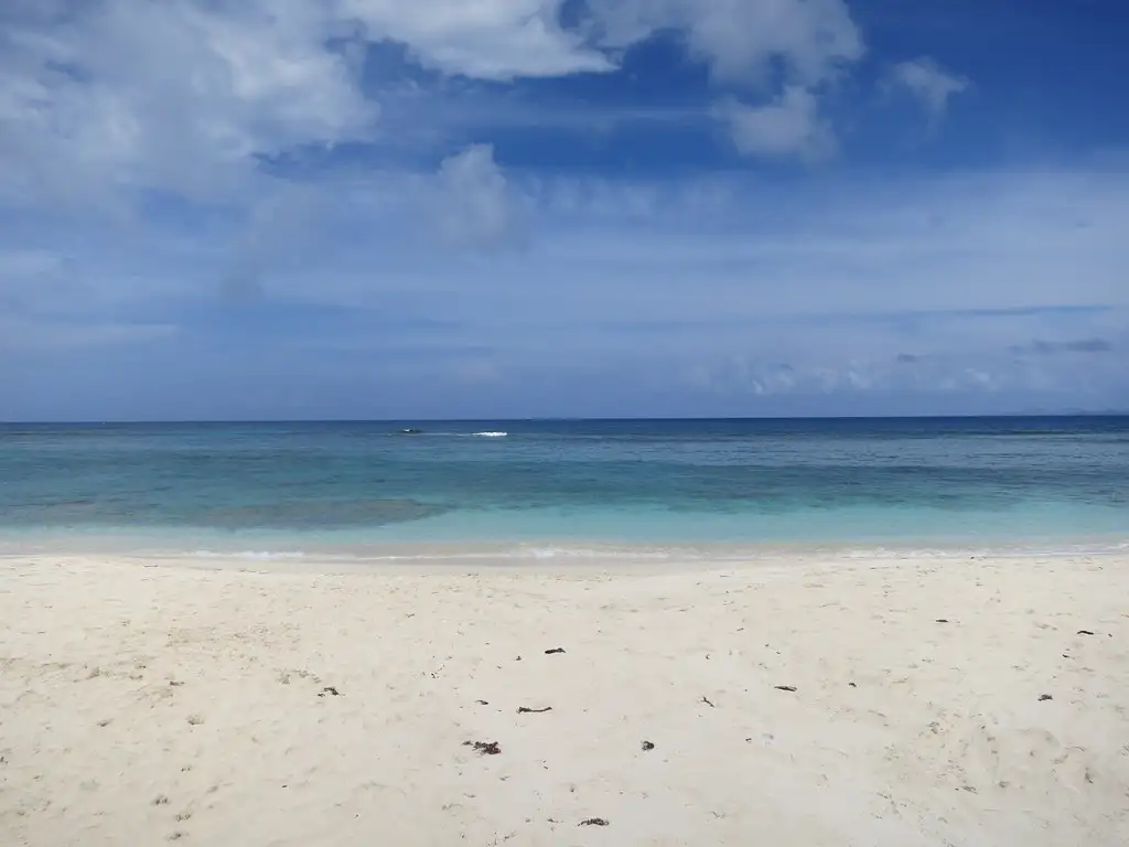 Empty white sand at Dawn Beach running down to turquoise water, with a line of surf breaking over the offshore reef and open Atlantic beyond