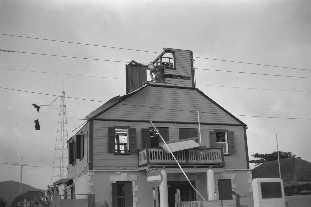 The front of the Philipsburg Courthouse during restoration, with workmen on the roof rebuilding the cupola and the shutters removed