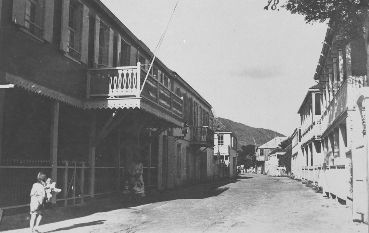 A dirt street in Philipsburg lined with low wooden and stone buildings with verandas and shuttered windows.