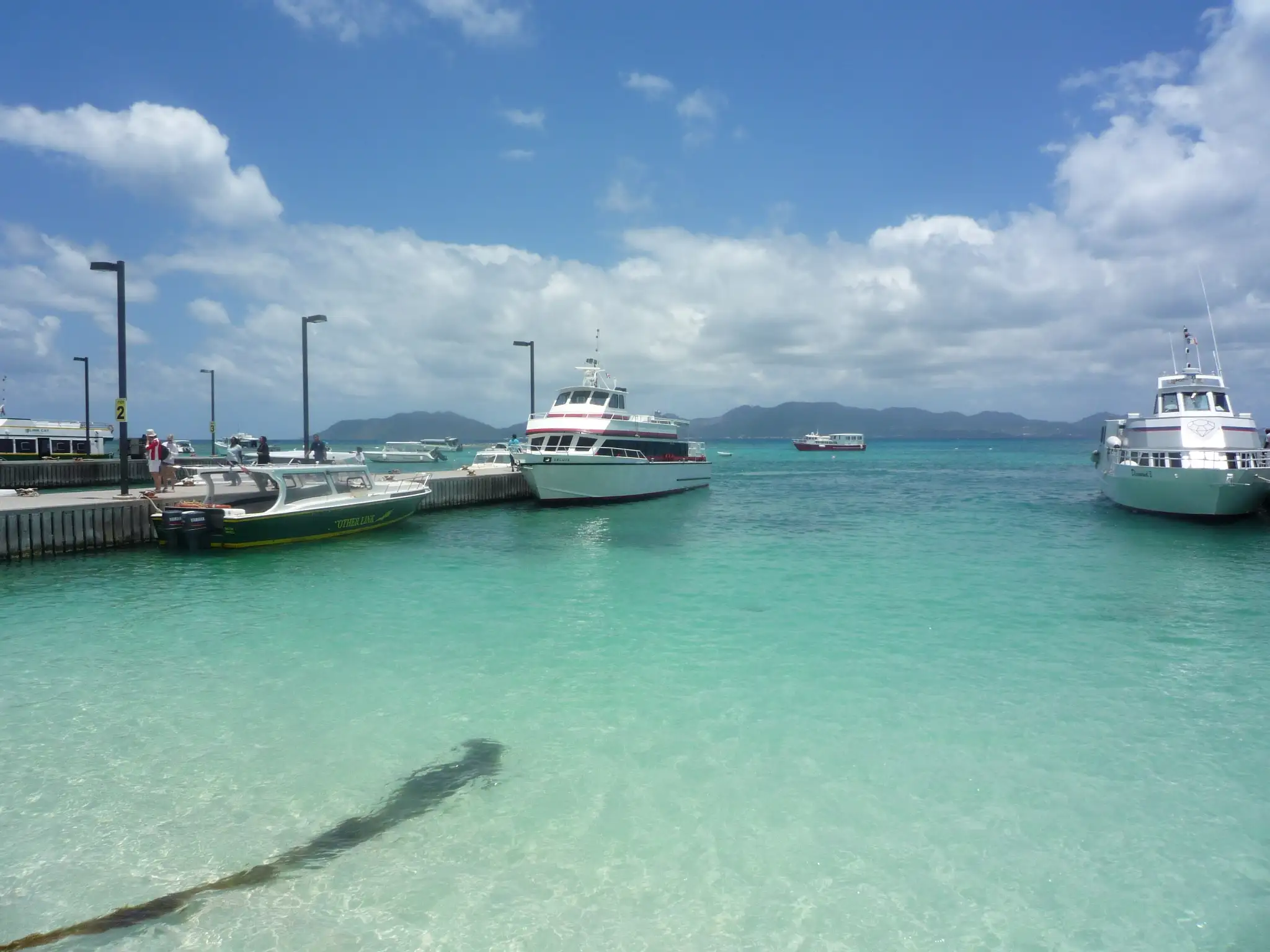 The pier at Blowing Point ferry terminal in Anguilla, with two small passenger ferries tied up alongside and a low terminal building behind
