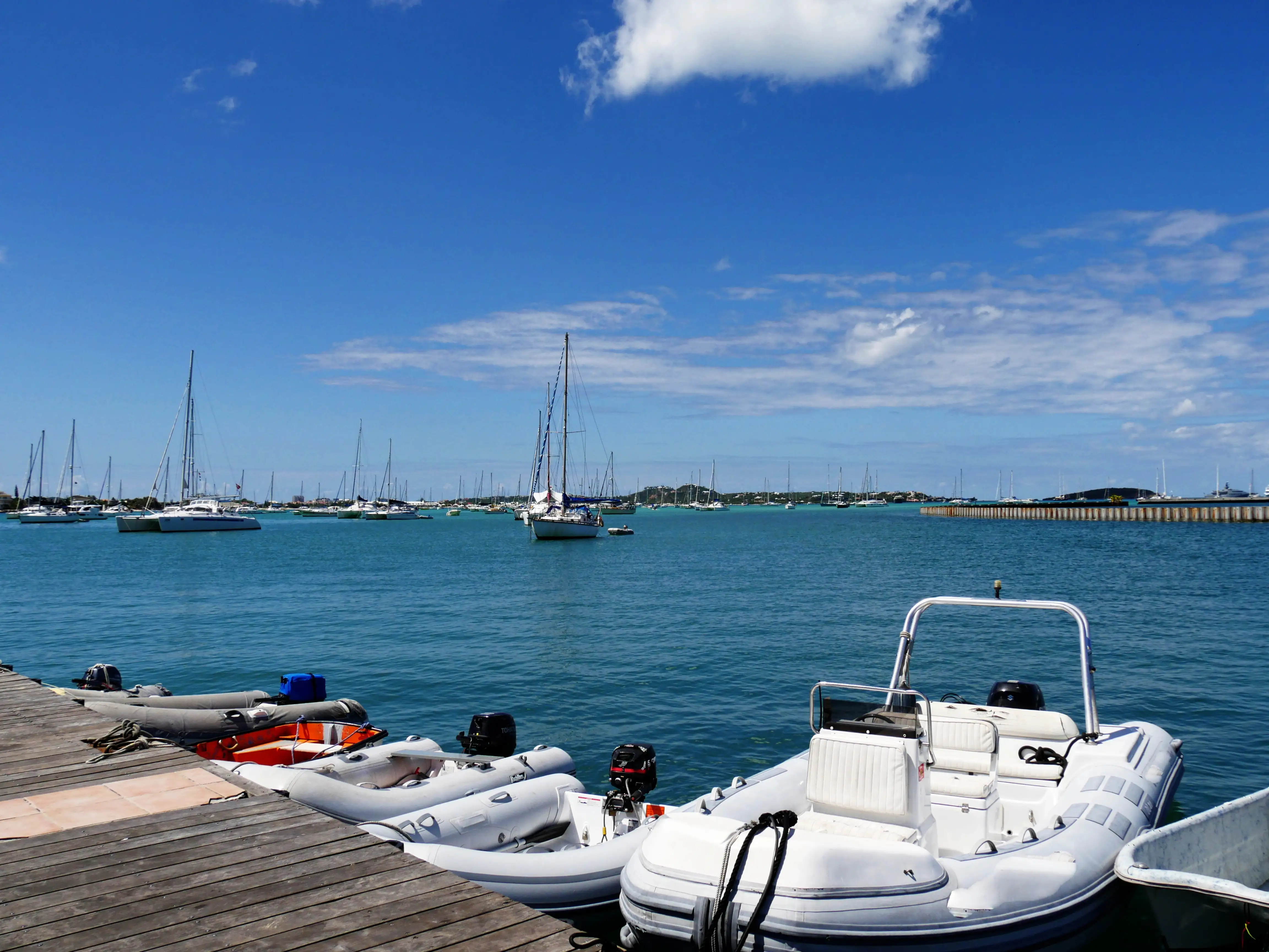 Yachts and small boats moored in the calm water of Marigot Bay under a bright sky, with the town along the shoreline