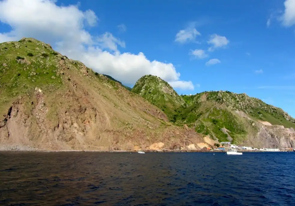 The ferry terminal building at Fort Bay on Saba, a low structure beside the water with the island cliffs rising behind it