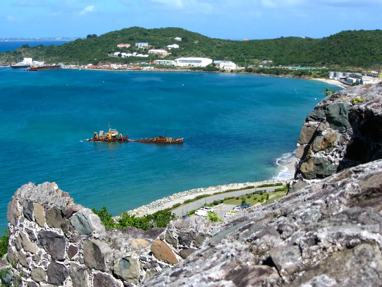 A wrecked boat lying half-submerged in the shallows of the bay below Fort Louis