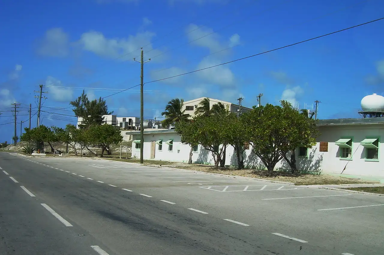 A two-lane road passing through a St. Maarten town, with low buildings and utility lines along the roadside