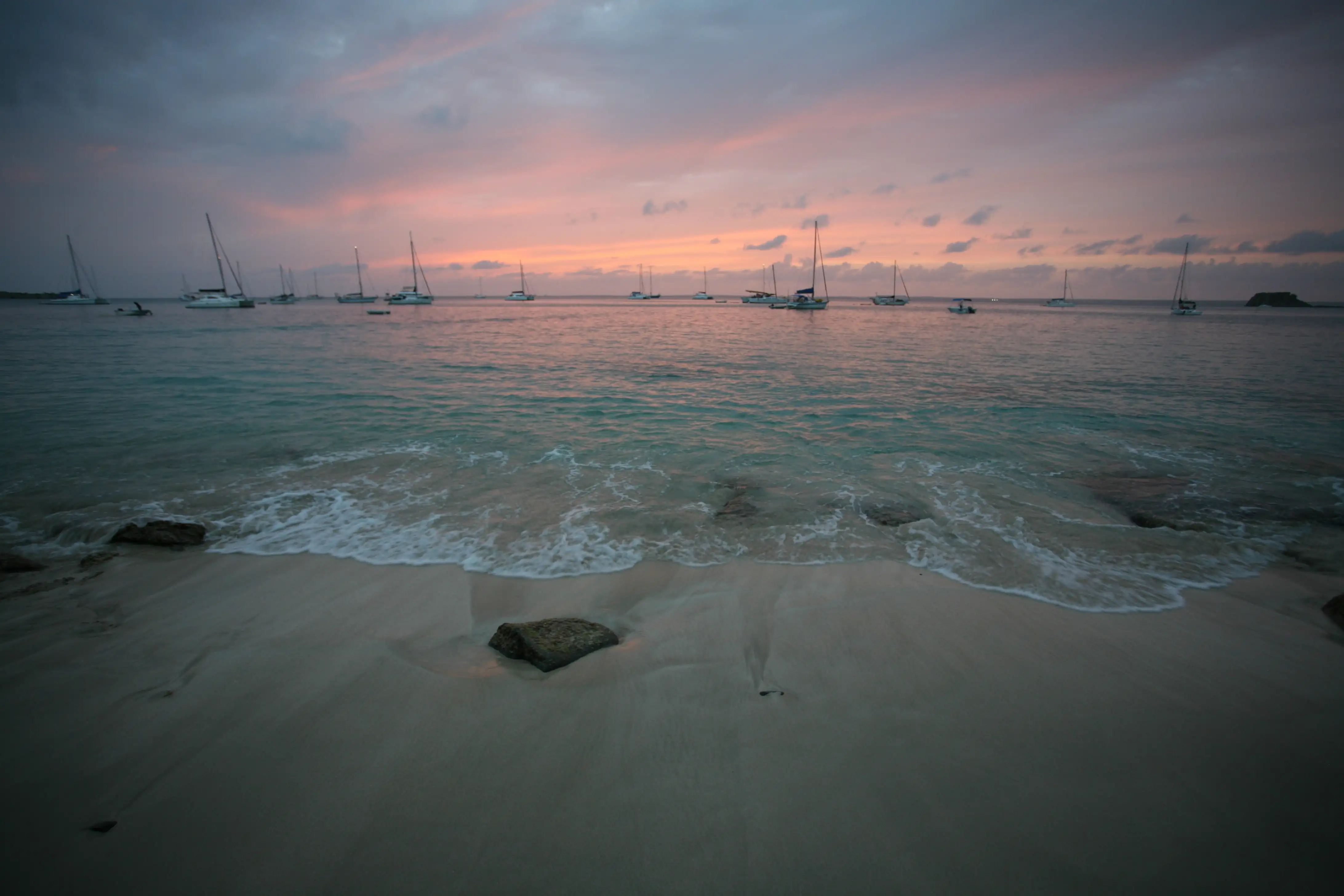 The sun going down over calm water at Grand Case, the sky and sea lit warm above a dark headland