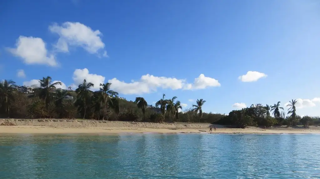 The empty white sand of Happy Bay on the French side of Saint Martin, backed by palms with no buildings anywhere in frame