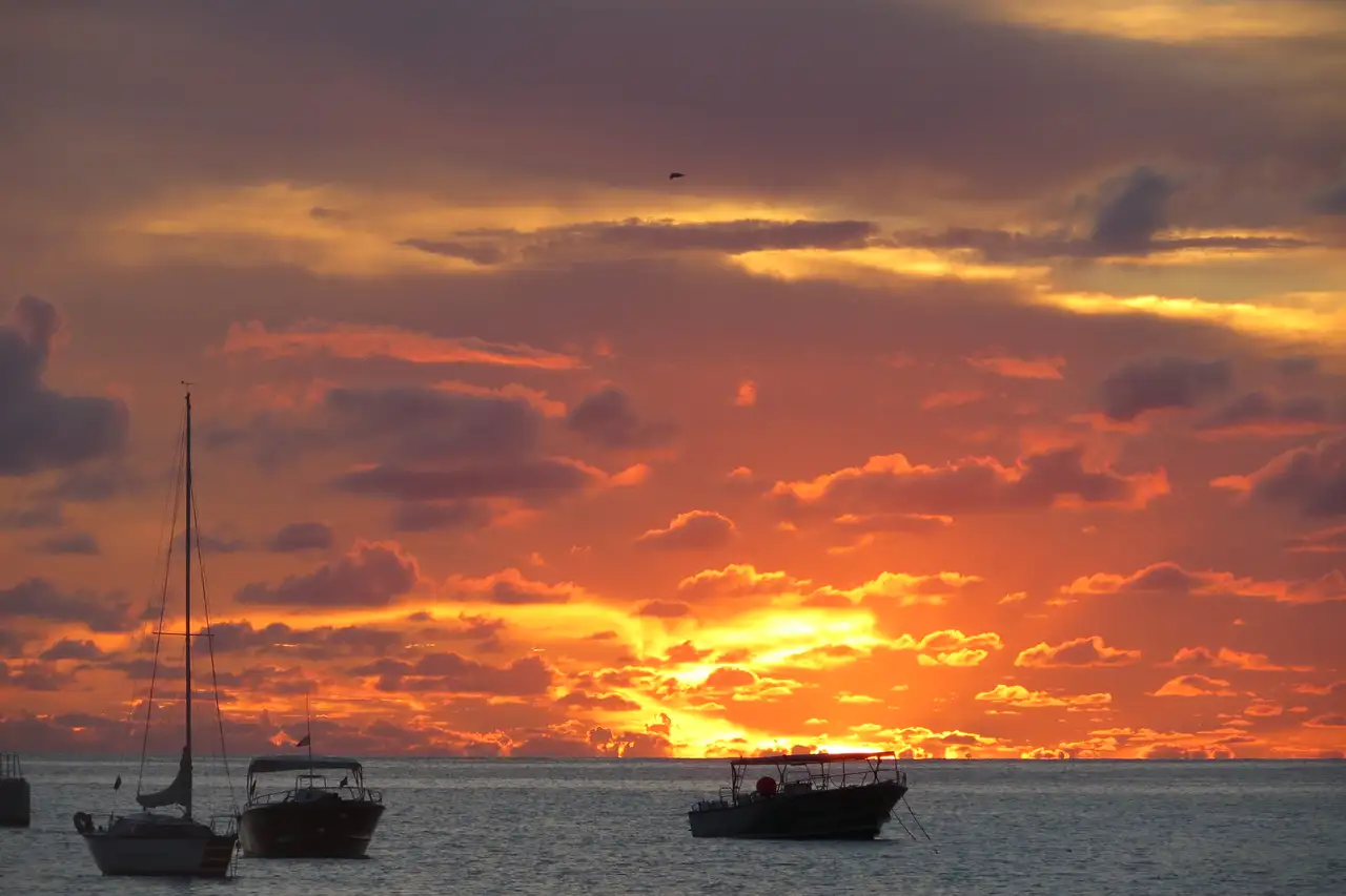 The sun setting over the water off Kim Sha Beach in Simpson Bay, the sky and sea lit orange behind a dark shoreline