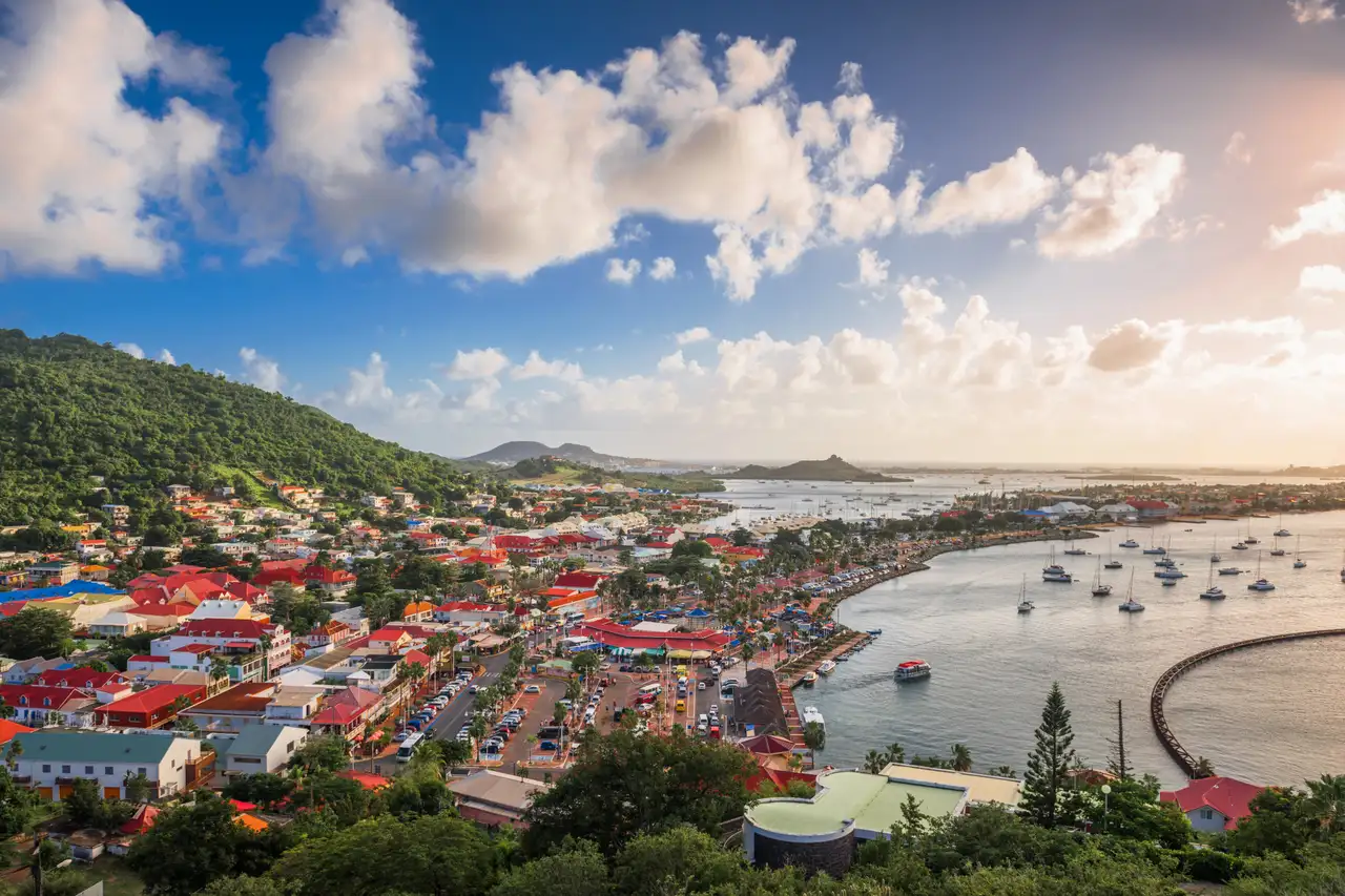 Aerial view of Marigot's harbor and hillside town at dusk, with boats moored in the bay