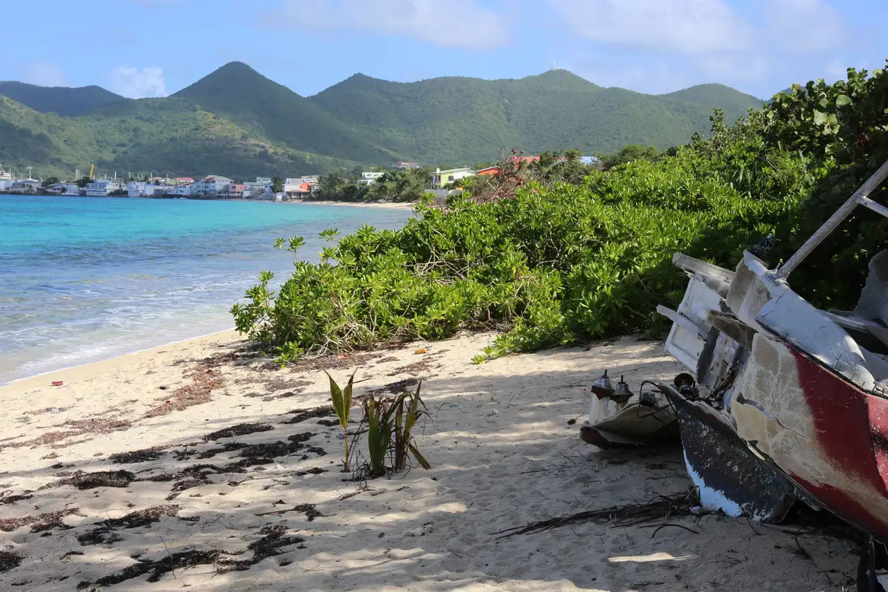 A small boat resting on the sand at the western end of Baie Nettlé, with the shoreline running away behind it