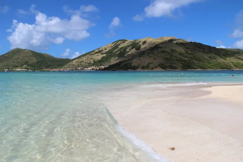 Shallow clear water running over pale sand at the edge of Pinel Island, with the bottom visible throughout