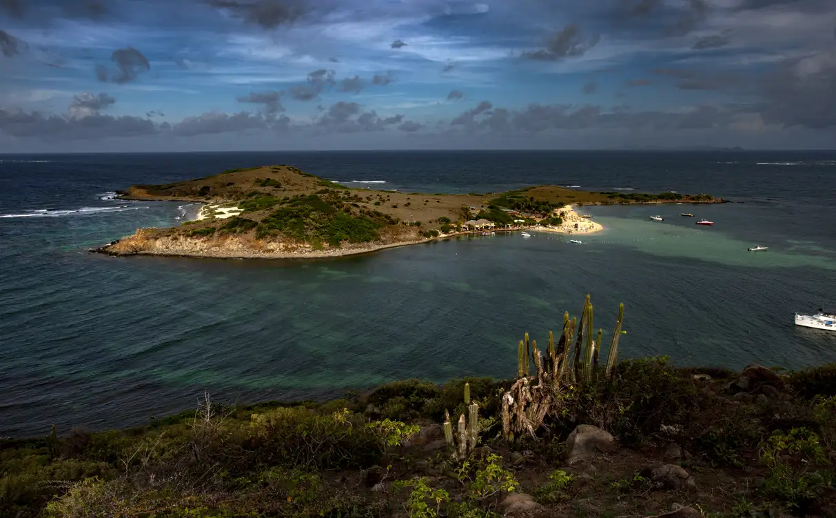 The low green islet of Pinel seen across shallow turquoise water from the St. Martin shore