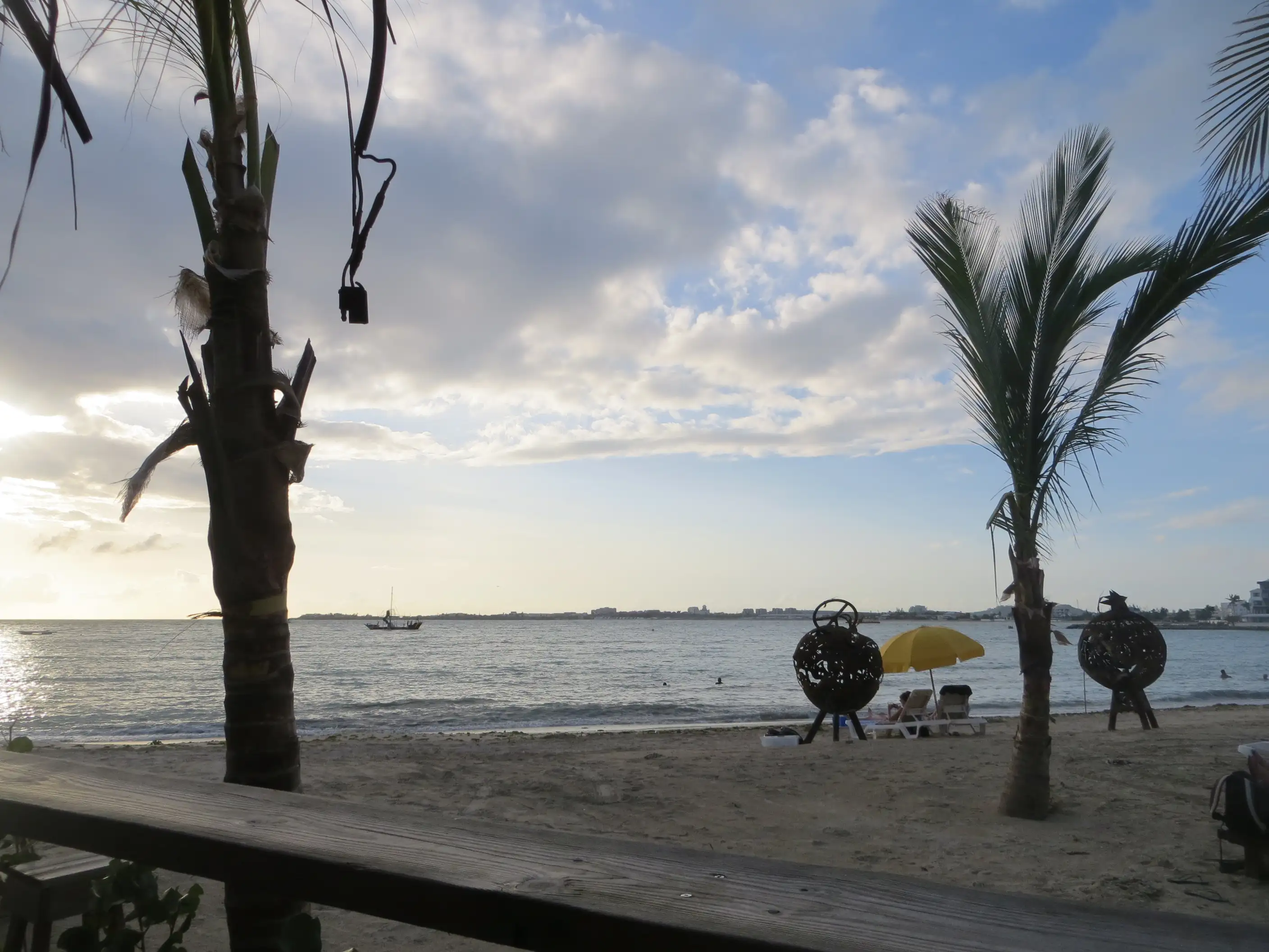 Simpson Bay seen from the sand beside a beach bar, the bay empty of boats under a bright sky